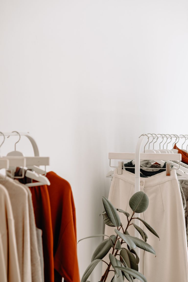 Image of clothing on a rail with a plant in front of them