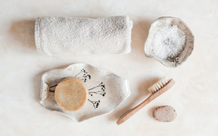 flatlay image of a face towel, toothbrush and bathroom items in neutral tones of cream and beige